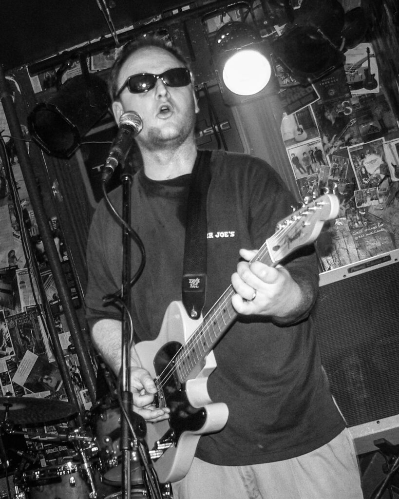 Black and white photo of Steve playing a Telecaster guitar at the Mississippi Brewing Company in Muscatine, Iowa