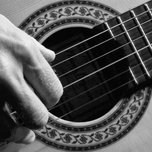 black & white image of classical guitar sound hole and player's fingers